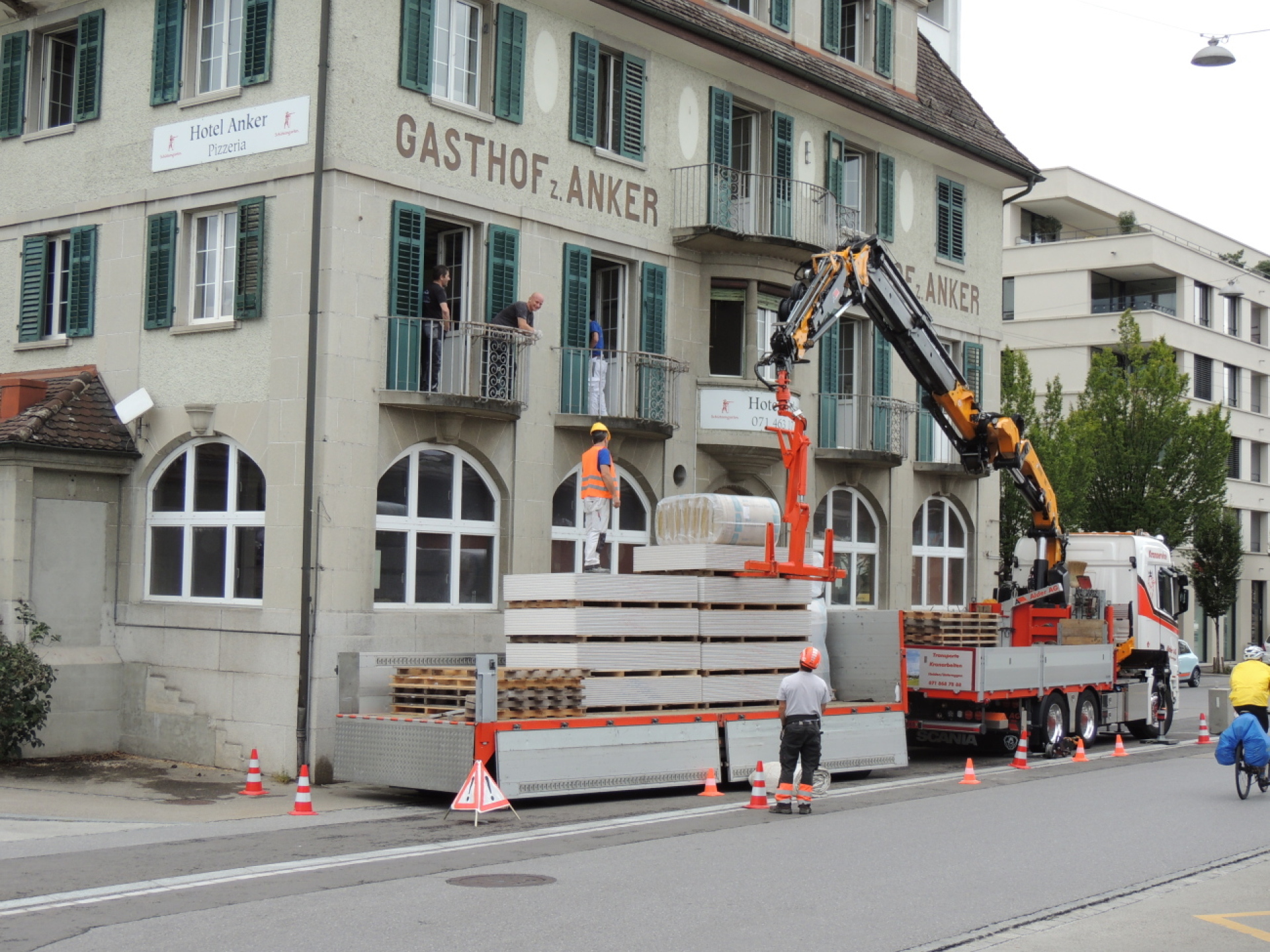 Kran hievt Paletten auf Hotel-Balkon