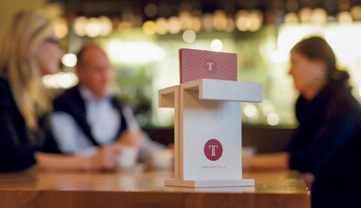 Der T-Holzsteller mit Logo auf dem langen Tisch im Restaurant Panem zeigt an: hier ist der Treffpunkt, der Ort, sich zu begegnen und auszutauschen. Foto: zVg.